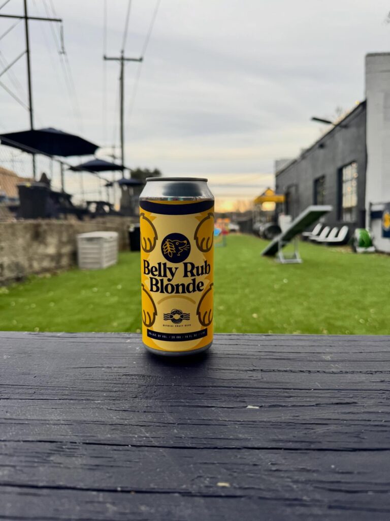 A can of our Belly Rub Blonde Ale in our off leash dog park.